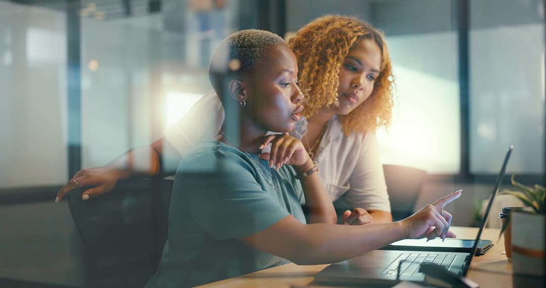 Two women analyzing data on a laptop